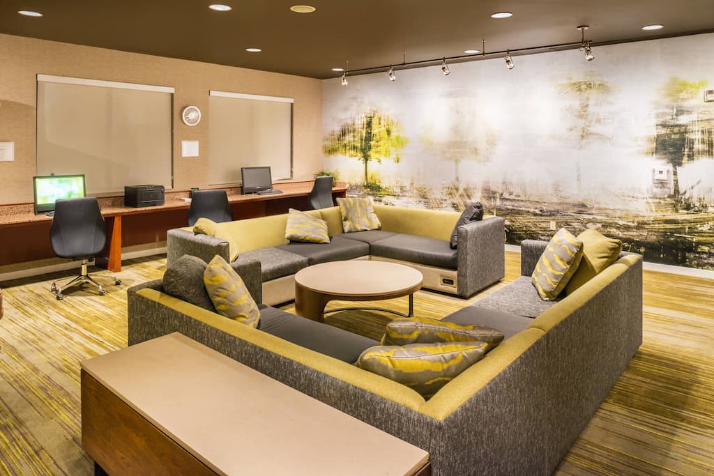 Contemporary lobby features a U-shaped sectional sofa with patterned cushions around a round table.