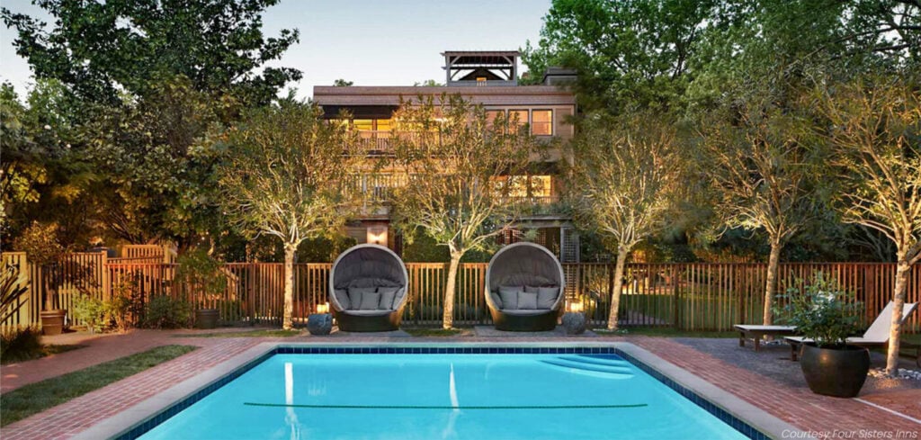 Illuminated pool with clear blue water, flanked by two round lounge chairs beneath softly lit trees.