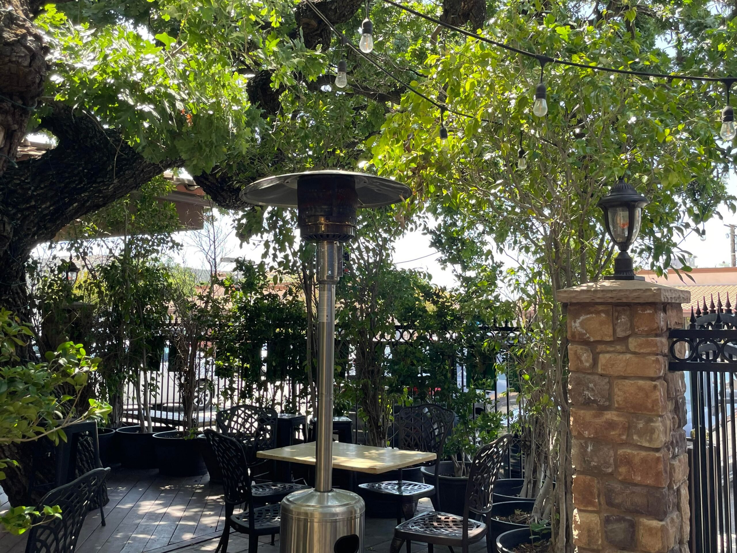 Patio heater stands unlit beside a table surrounded by metal chairs.