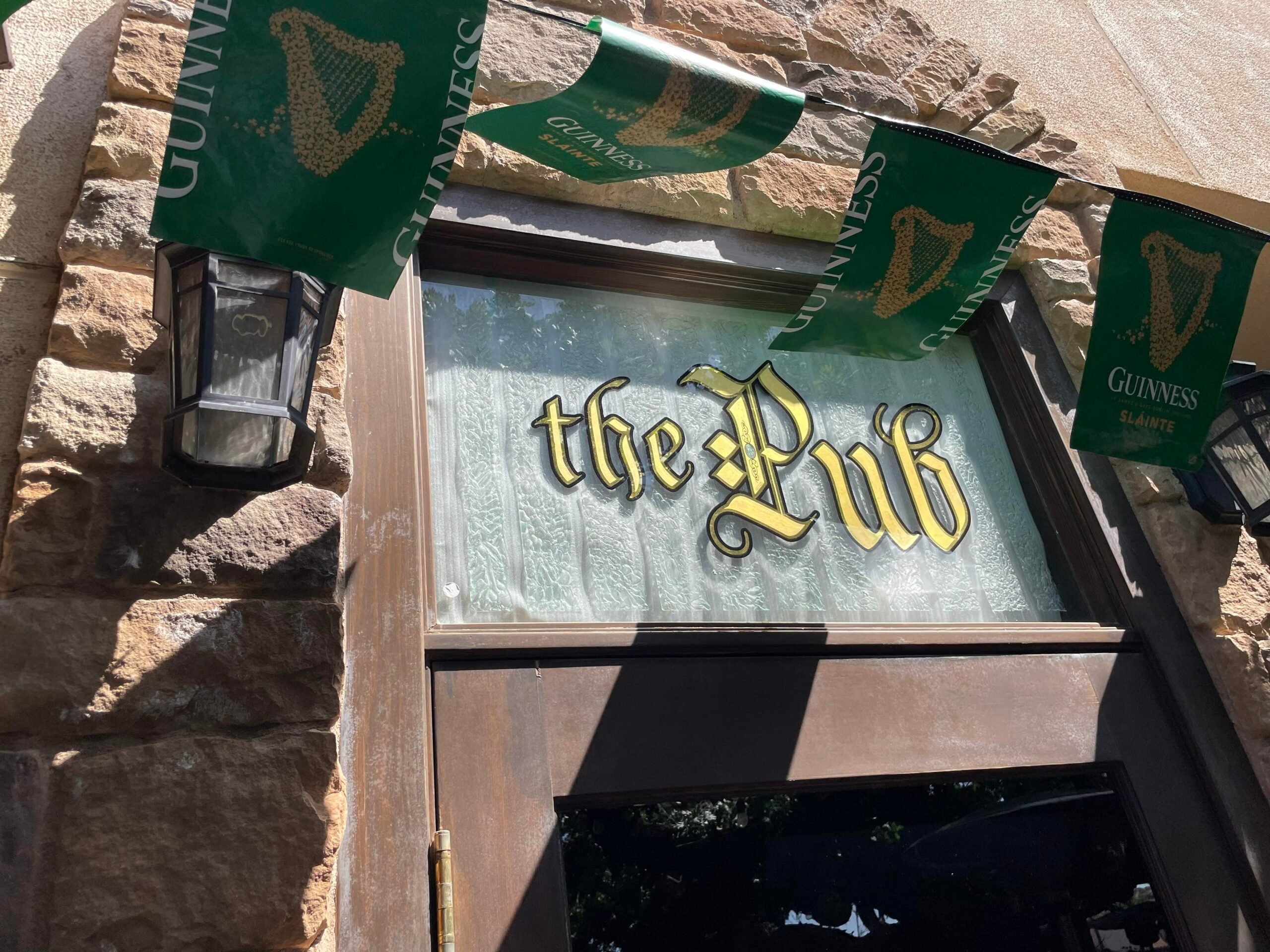 Pub entrance sign reads "the Pub" in gold letters above a rustic stone wall.