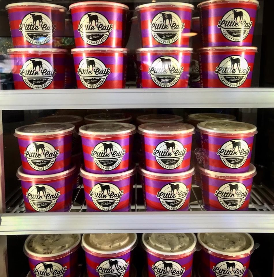 Ice cream containers with "Little Calf" logo stacked in a refrigerated display.