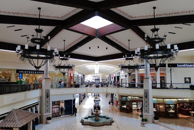 Shopping mall interior showcasing an ornate fountain in the center, surrounded by stores like Crabtree & Evelyn and BareMinerals.