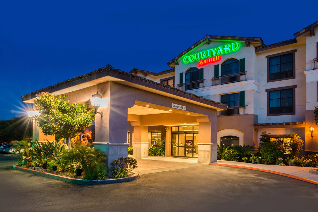 Courtyard by Marriott hotel entrance lit warmly at night, featuring decorative plants and a covered driveway.