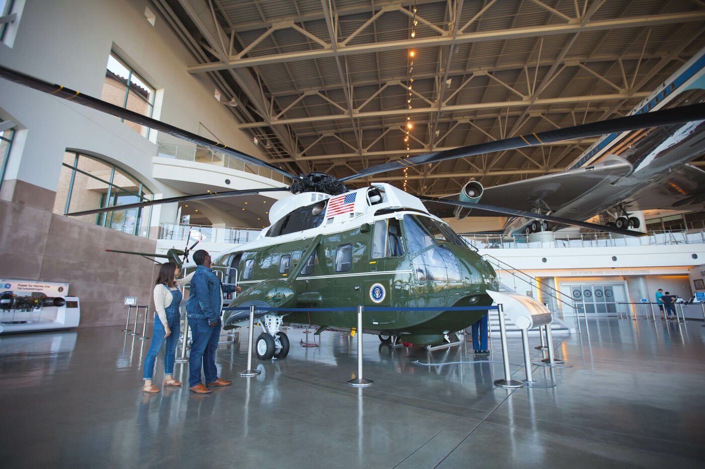 A military helicopter with the presidential seal and American flag displayed, sits in a spacious museum.