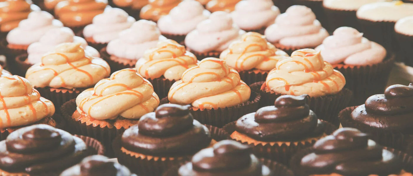 Assorted cupcakes displayed neatly in rows, topped with creamy frosting in chocolate and caramel flavors, creating an inviting dessert spread, perfect for a festive or celebratory occasion in Conejo Valley.
