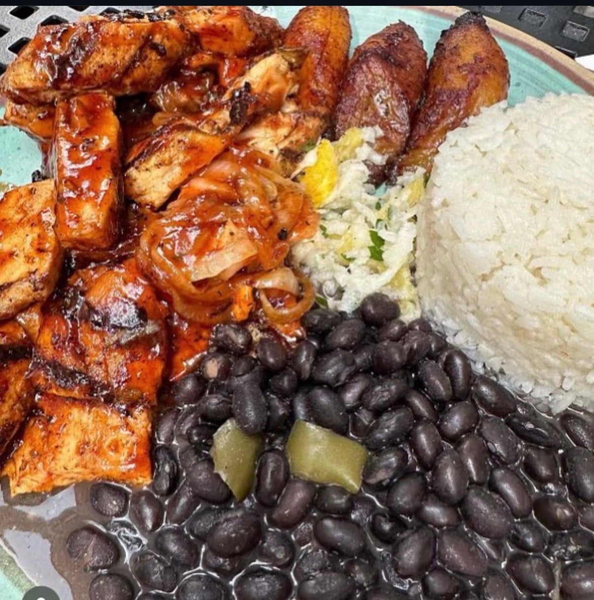 Traditional Cuban plate with grilled chicken, black beans, white rice, sweet plantains, and potato salad.