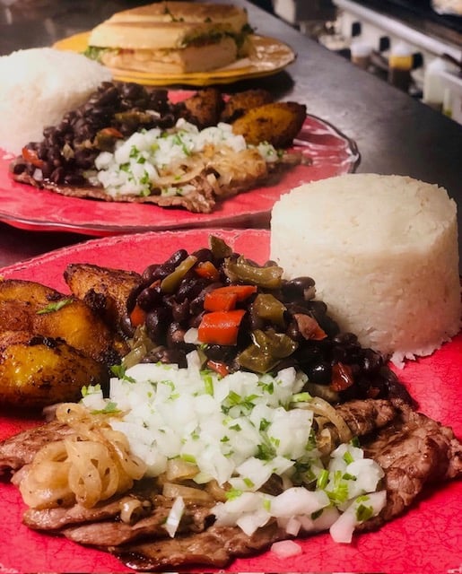 Cuban entrée with grilled steak topped with onions, served with white rice, black beans, and sweet plantains.