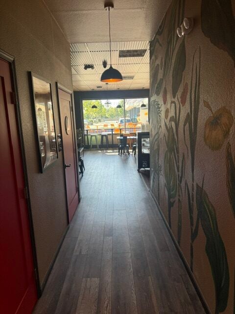 Hallway leading into a cozy café dining area with tropical mural walls, pendant lighting, and front window seating.